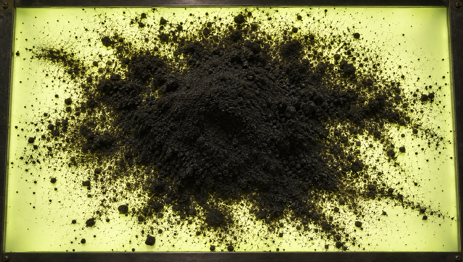 The poured heap of black sand on the glowing table