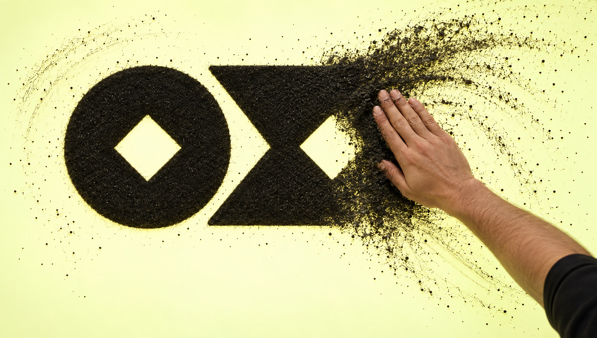 A hand mid-sweep revealing the mark in sand